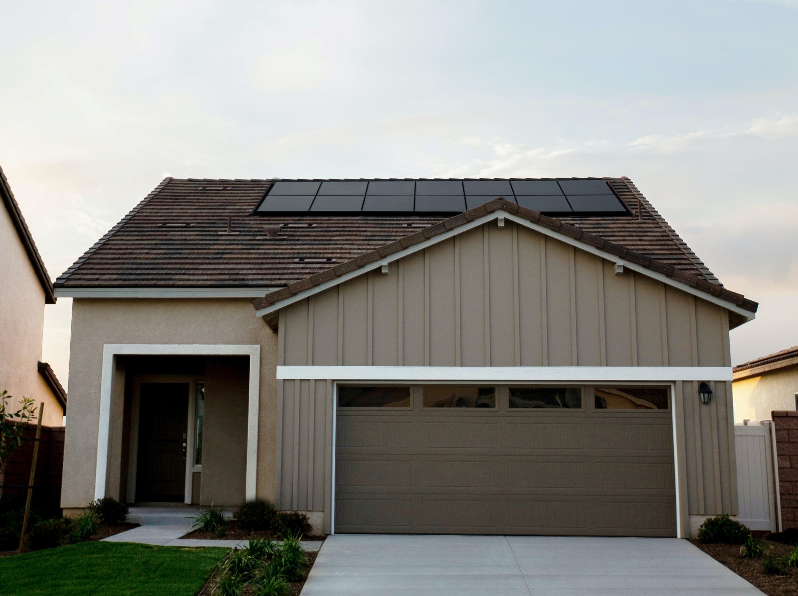California suburban home with solar panels on roof; sunset in the background.