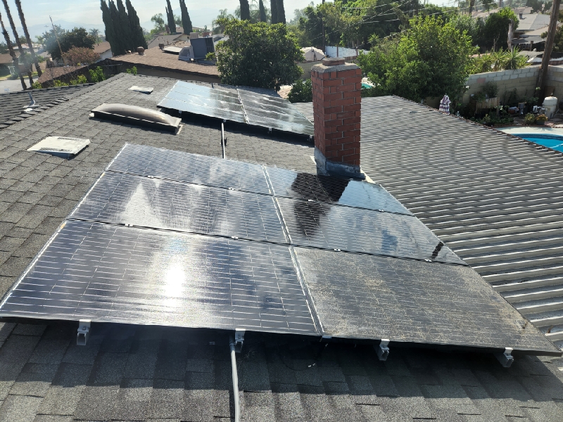 Two blocks of solar panels with a chimney in between on a roof in Fontana