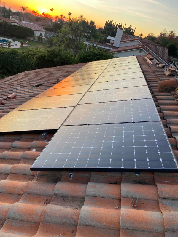 Solar panels on a tile roof of a home, at sunset.
