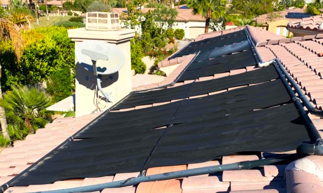 Solar panels near a chimney and satellite dish on the roof of a home in Rancho Mirage.
