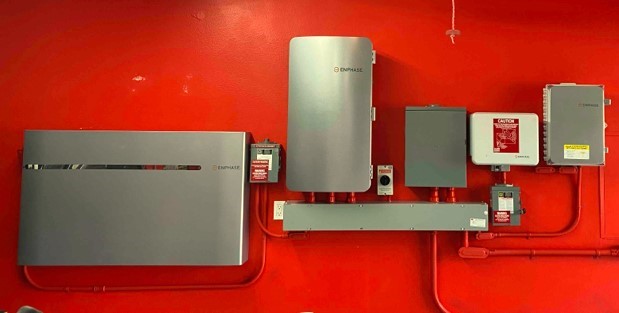 The battery system and wiring for solar panels mounted on a red wall