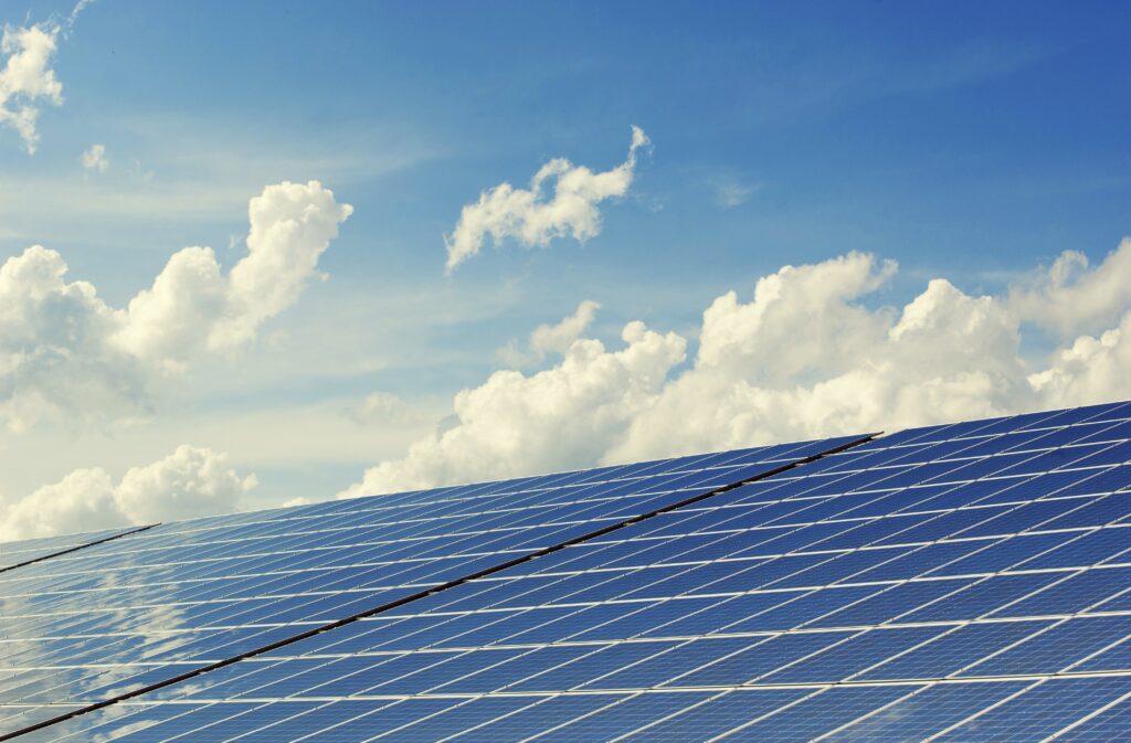 Close view of solar panels; sunny sky with some clouds in the background.